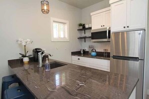 A modern kitchen with a marble countertop, stainless steel appliances, and white cabinetry. - Tiny Home near Zion with Rooftop Stargazing Deck (Orderville)