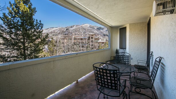 A balcony with a table and chairs, a view of a mountain, and a tree. - Pool, Hot Tub, Fitness Room, Garage, 2-balconies, Short Walk to Ski Slopes (Steamboat Springs)