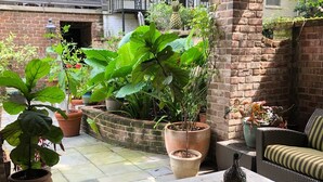 An outdoor patio with potted plants, a wicker sofa, and a table.