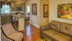 A kitchen with a central island, a dining area with a sofa, and a painting on the wall.