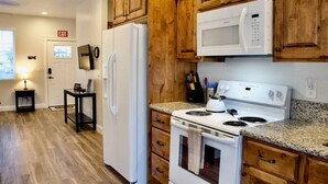 A kitchen with wooden cabinets, a white refrigerator, a microwave, and a stove.