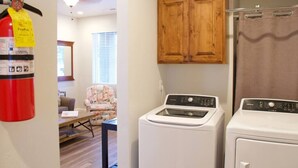 A laundry area with a washing machine, dryer, and wooden cabinets.