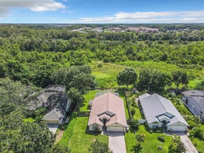 A residential area with multiple houses, each with a distinct roof design, surrounded by lush greenery and a clear sky. - Conservation View, Hot Tub, Very Private (Kissimmee)