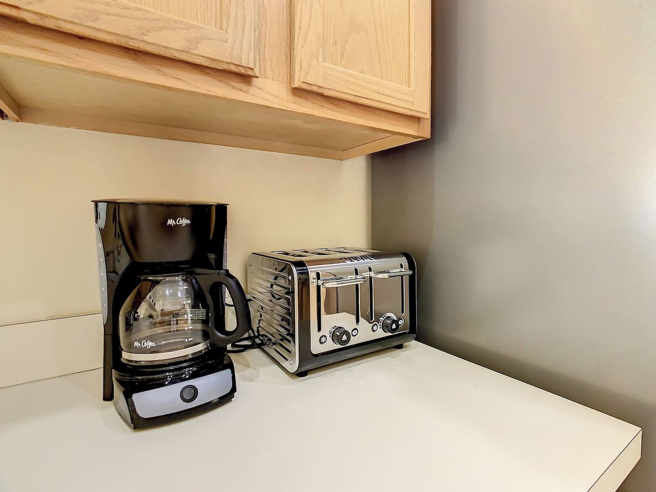 Una cocina con cafetera y tostadora sobre una encimera blanca.