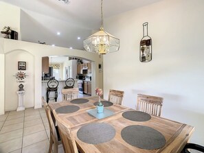Un comedor con mesa de madera, sillas y una araña.