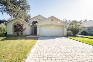 A single-story house with a garage, a paved driveway, and a small lawn area.