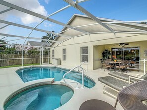 Piscina exterior techada con zona de patio, incluyendo asientos y una mesa.