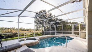 Una piscina al aire libre techada con sillas de descanso y un jacuzzi.