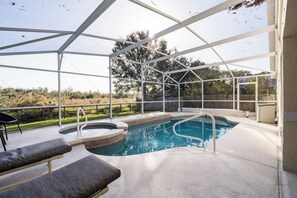 A covered outdoor swimming pool with lounge chairs and a hot tub. - Conservation View, Hot Tub, Very Private (Kissimmee)