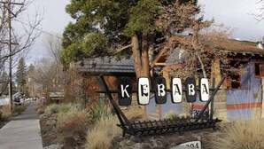 Et skilt med navnet "KERABI" i store bogstaver, en stenhængt sti og en rustik bygning med et metal tag.