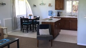 A modern kitchen with wooden cabinets, a dining area with a table and chairs, and a ceiling fan.
