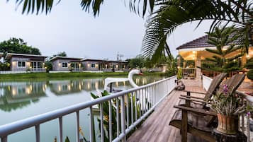 A lakeside deck with a swan, wooden benches, and a gazebo.