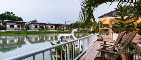 A lakeside deck with a swan, wooden benches, and a gazebo.