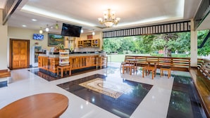 A spacious lobby with a bar area, seating, and a large window overlooking a garden.