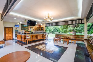 Un vestíbulo amplio con una zona de bar, asientos y un ventanal grande con vistas a un jardín.