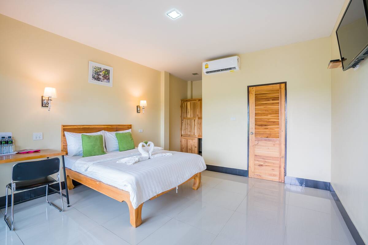 Habitación de hotel con cama, escritorio, silla, lámpara de pared y unidad de aire acondicionado.
