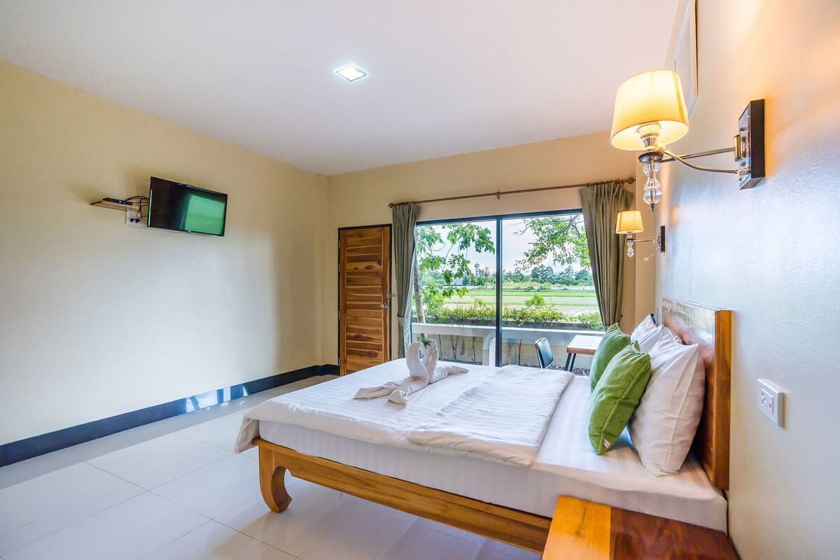 Habitación de hotel con cama, televisor, ventana con vistas y una mesa con sillas.