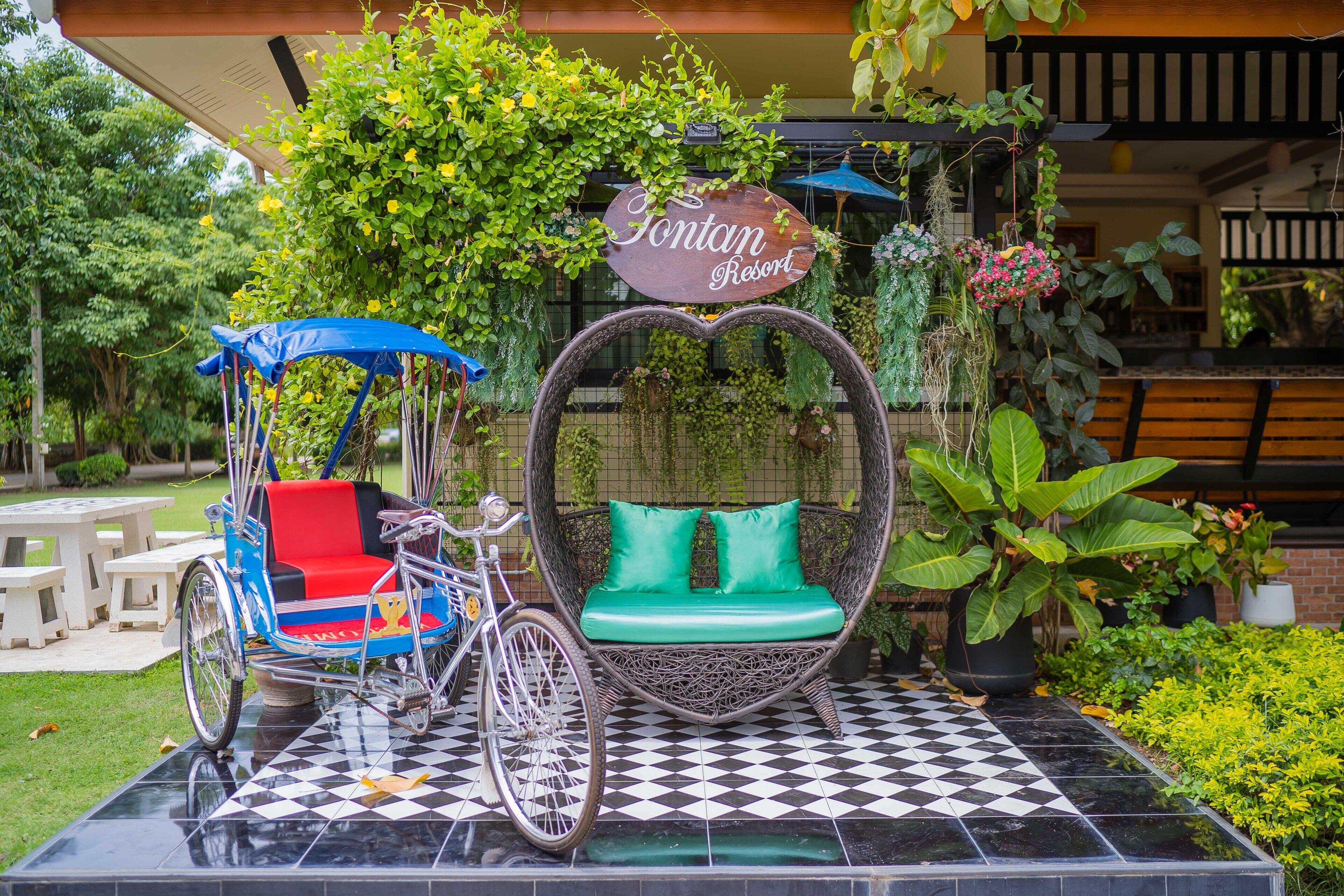 A wicker swing chair with green cushions, a bicycle, and a sign that reads "Fontan Resort."