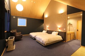 A bedroom with a large bed, a desk, and a chair. There is a window and a heater on the floor. - Element (Nakafurano)