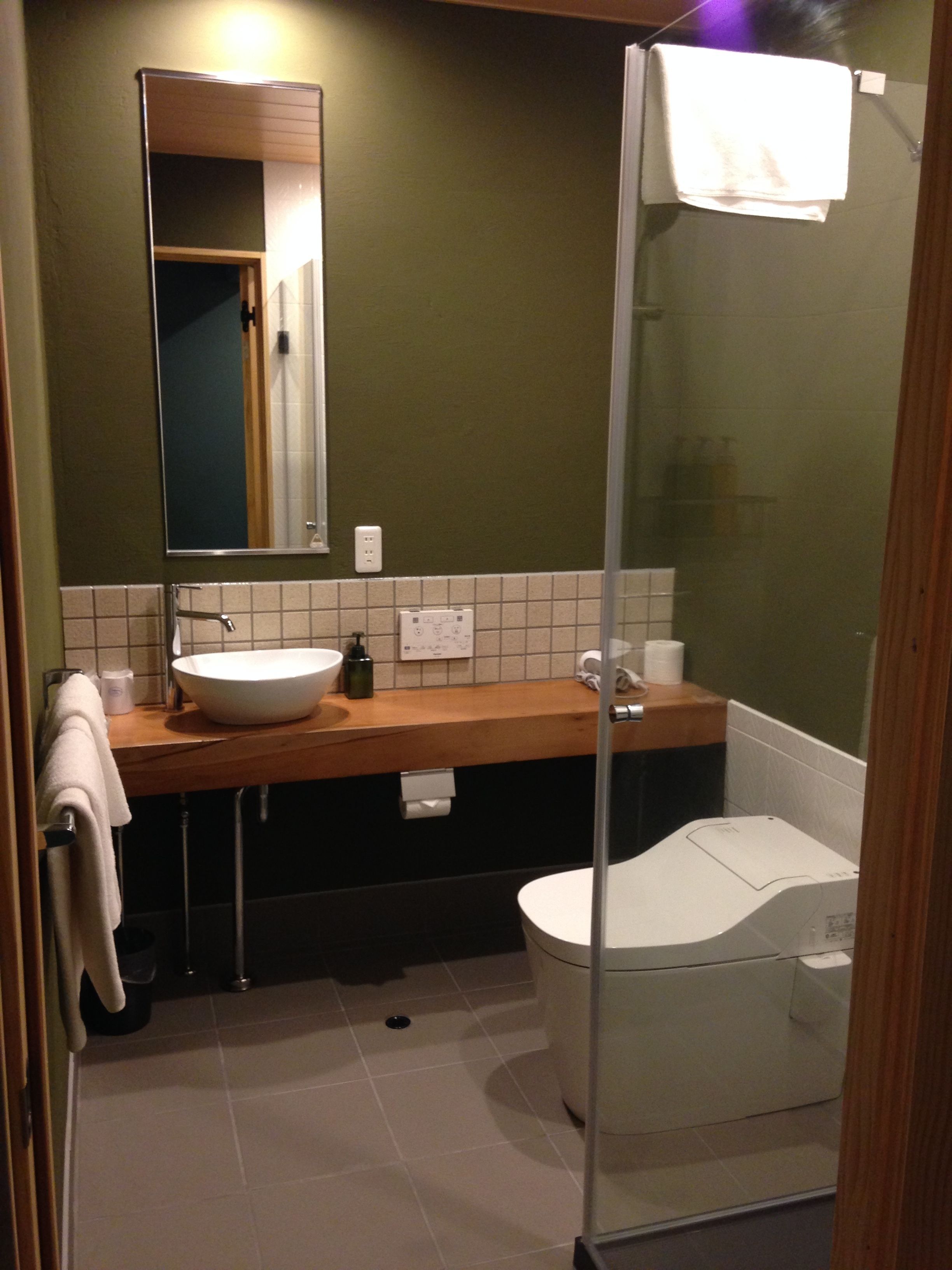 A modern bathroom with a white sink, a mirror, and a glass-enclosed shower.