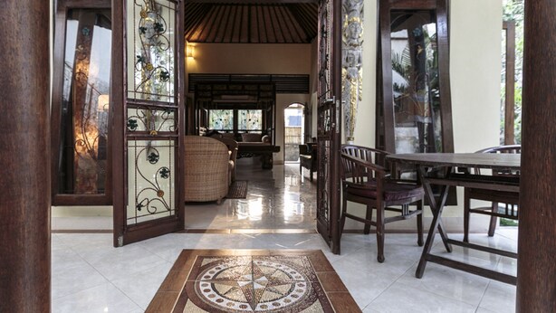 An open doorway leading to a room with a tiled floor, a wooden table, and chairs. - Murni's Villa Kelor (Ubud)