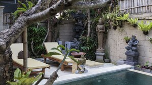 A pool area with lounge chairs, a statue, and various plants. - Murni's Villa Kelor (Ubud)