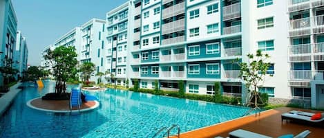 A modern hotel with a swimming pool, multiple balconies, and a wooden deck area.