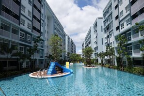 Un moderno edificio residencial con piscina, tobogán y terraza solárium.