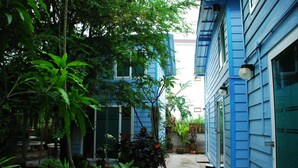 A courtyard with blue buildings, potted plants, and a concrete pathway. - Baan Kum Siri (Hua Hin)