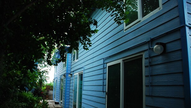 A blue house with a front door, a sliding glass door, and a small porch area. - Baan Kum Siri (Hua Hin)