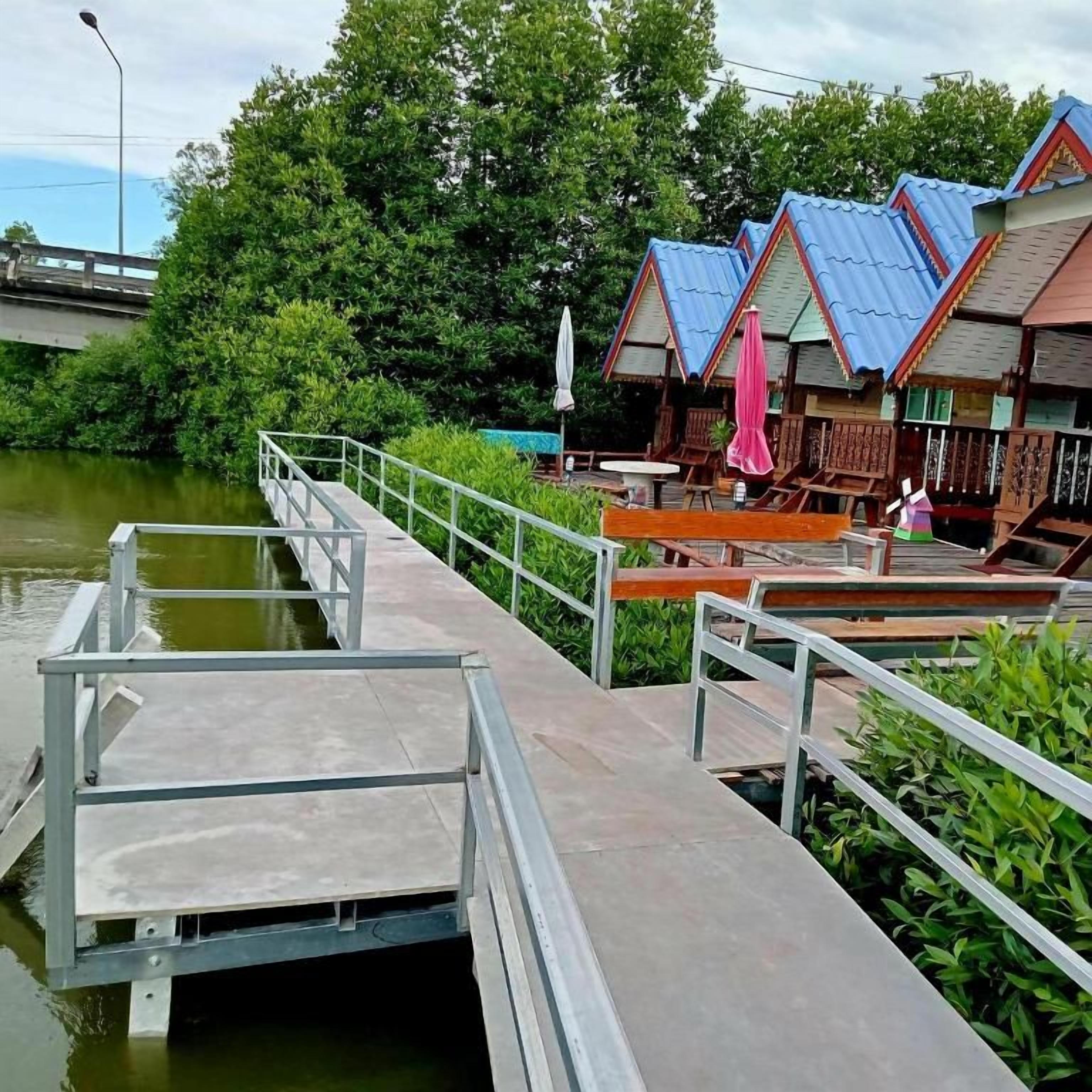 A riverside walkway with wooden benches and a metal railing.