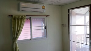 Quarto com janela, ar condicionado e cortina.
