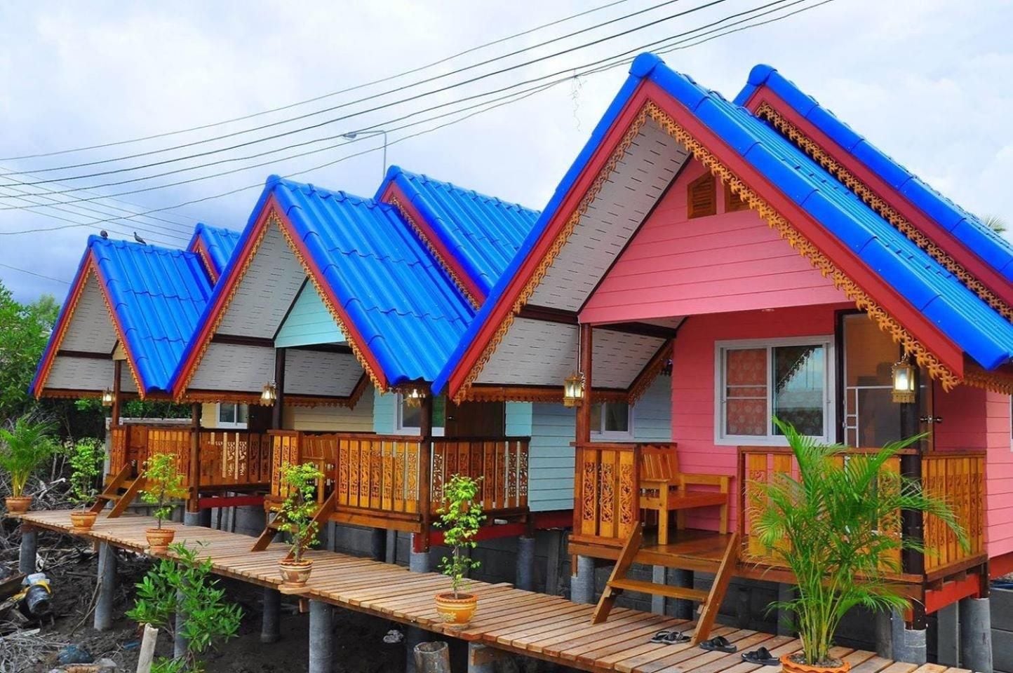A row of elevated wooden houses with blue roofs and a wooden deck in front.