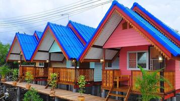A row of elevated wooden houses with blue roofs and a wooden deck in front.