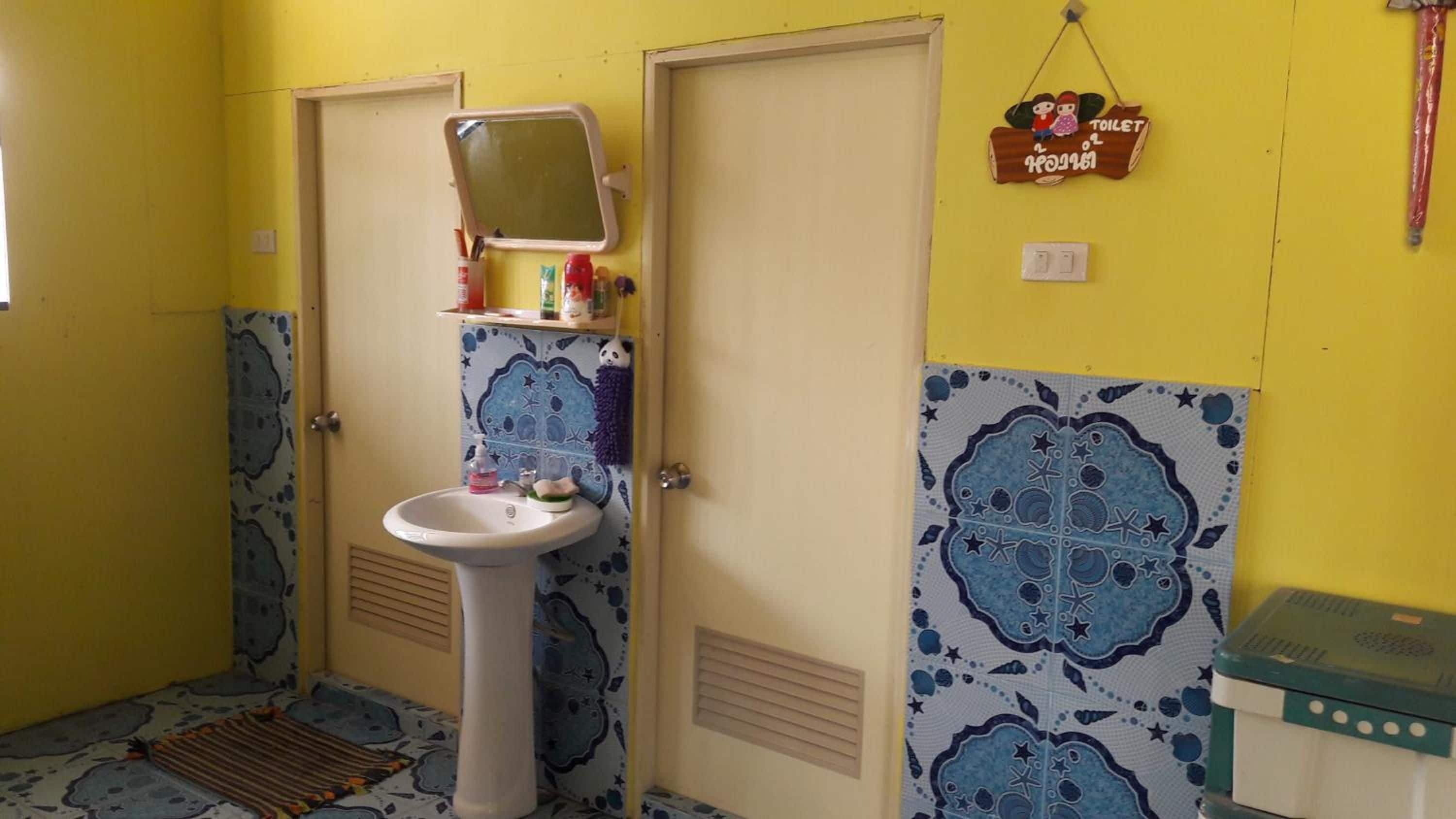 A bathroom with a sink, mirror, and a toilet sign on the wall.