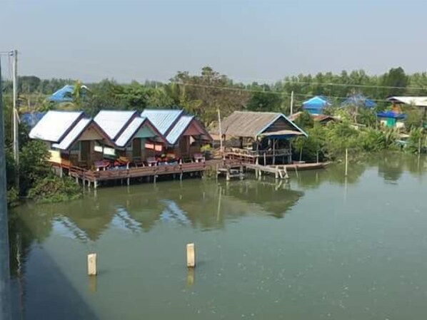 Varias casas flotantes con una terraza de madera y un pequeño muelle.
