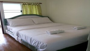 Cama bem arrumada com lençóis brancos e duas toalhas sobre ela.