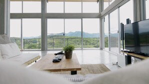 Un salon moderne avec une grande télévision, une table basse en bois et une plante.