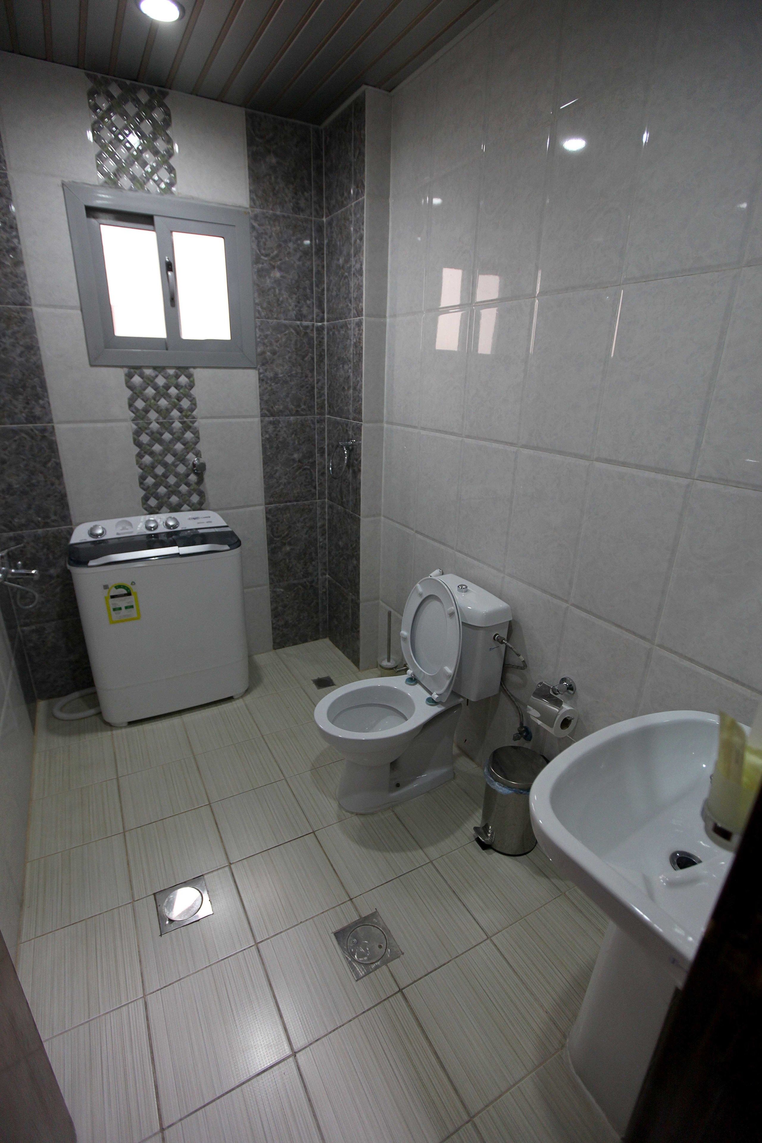 Un baño con inodoro, lavamanos y lavadora.
