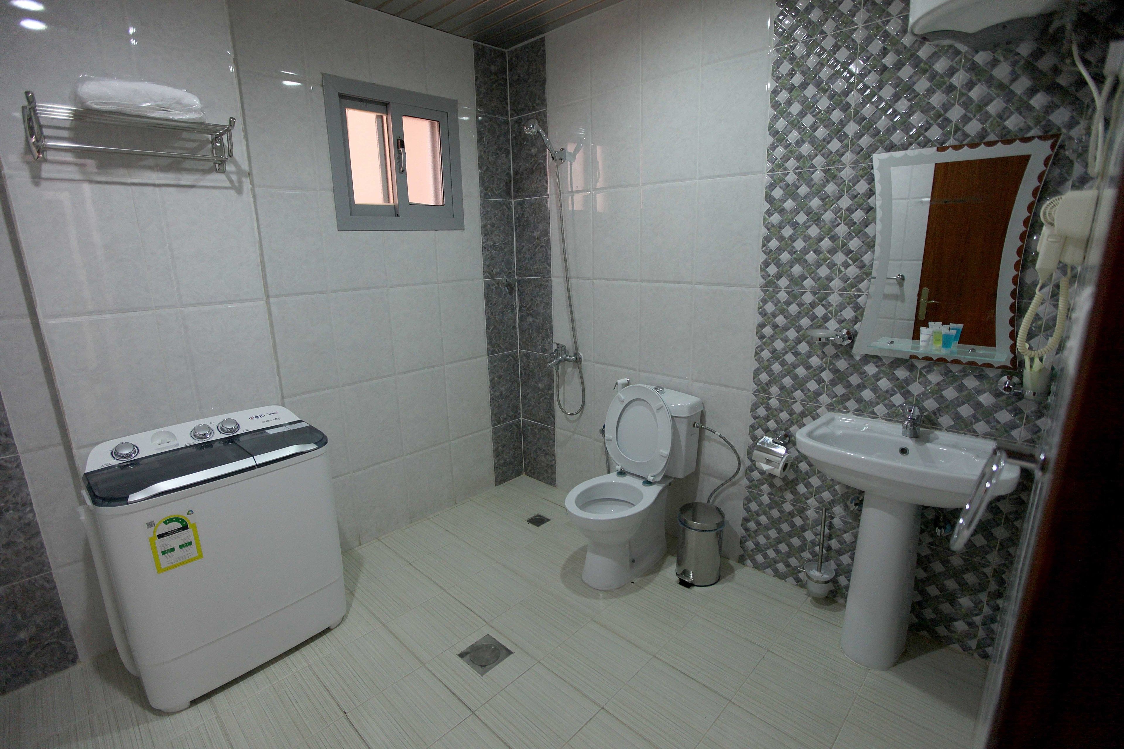 Une salle de bain équipée de toilettes, d’un lavabo, d’une douche et d’un lave-linge.