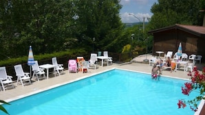 A rectangular swimming pool with clear blue water, surrounded by white lounge chairs and umbrellas. - Agriturismo Le Francesche (Nocera Umbra)