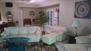 Ein Wohnzimmer mit einem weißen Sofa, einem Couchtisch, einer Lampe und einem Blumentopf.
