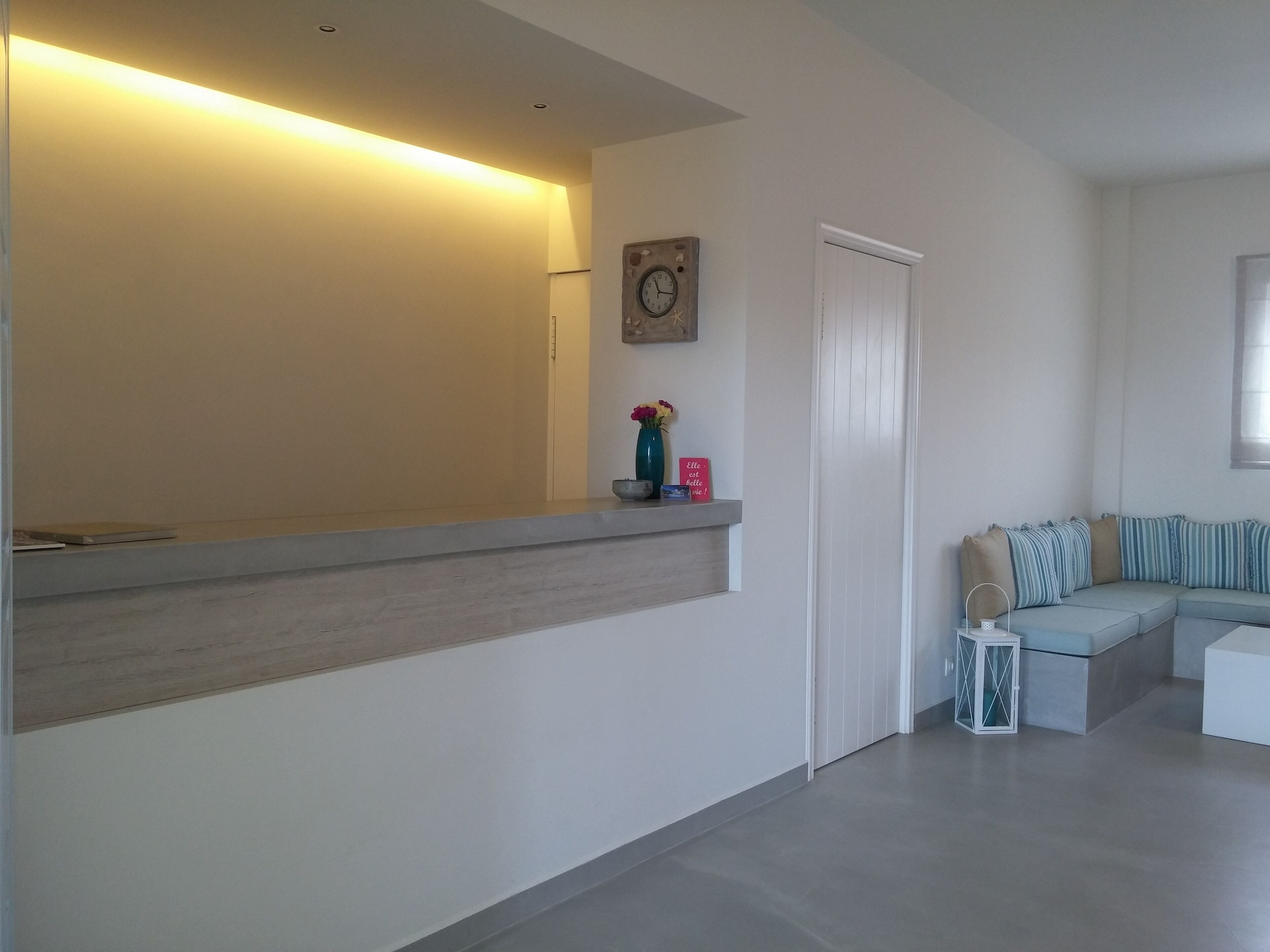 Una sala de estar moderna con un banco empotrado, una puerta blanca y un reloj en la pared.