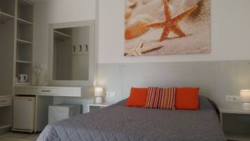 Un dormitorio con cama, escritorio, espejo y un cuadro en la pared de una estrella de mar.