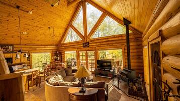 A log cabin interior with a dining area, living room, and fireplace.