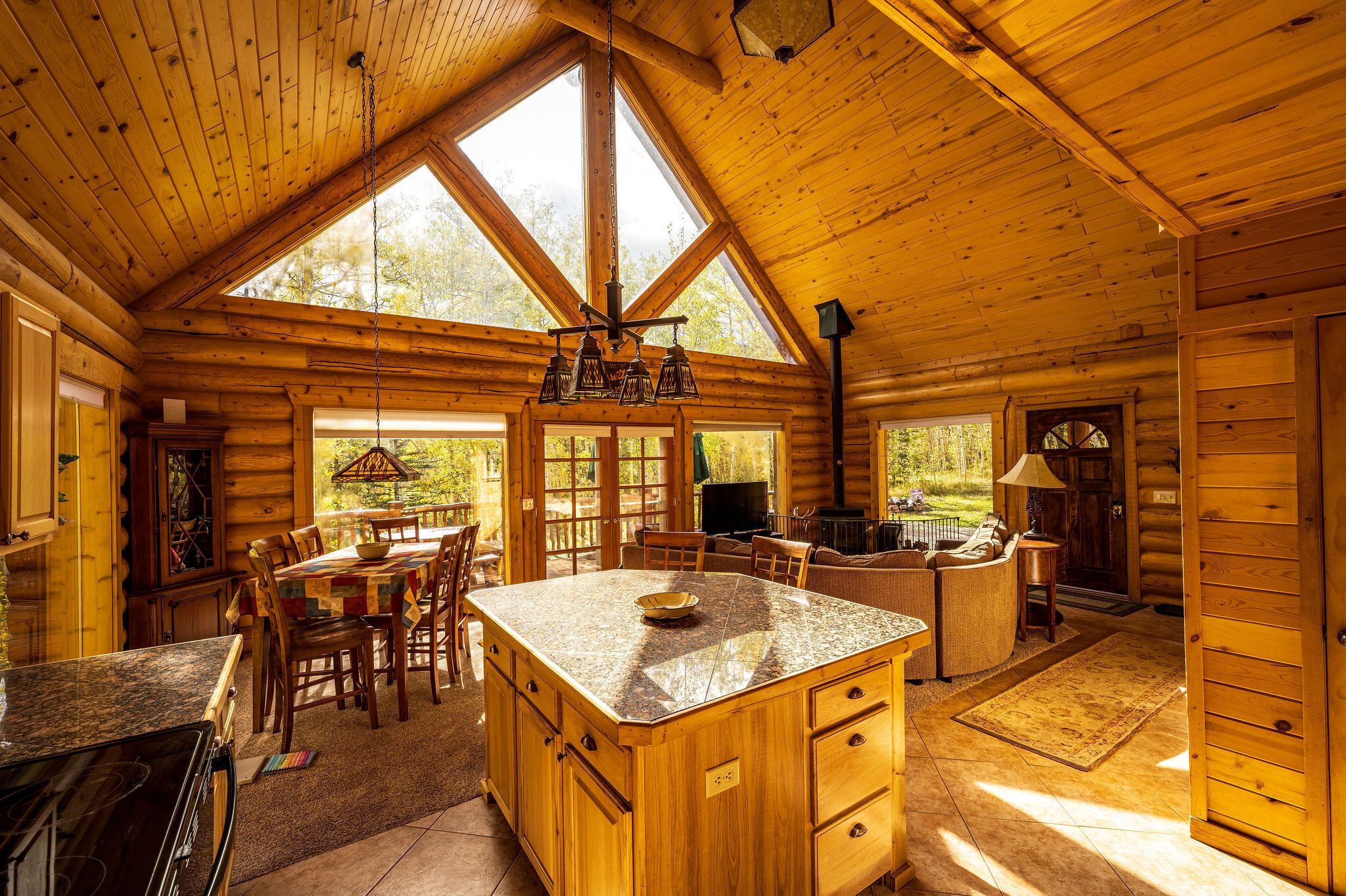 A spacious log cabin interior with a large kitchen area, dining space, and a cozy living area.