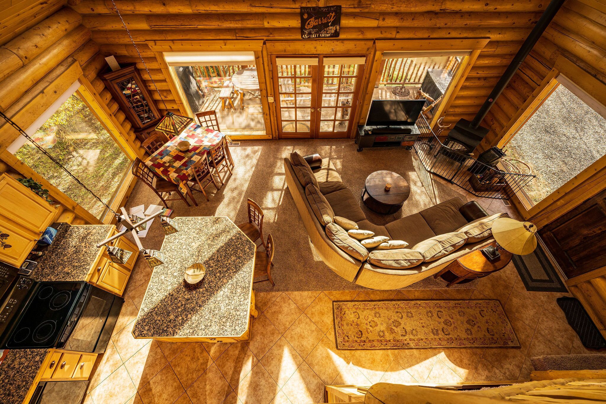 A log cabin interior with a dining area, a sofa, a fireplace, and a kitchen.