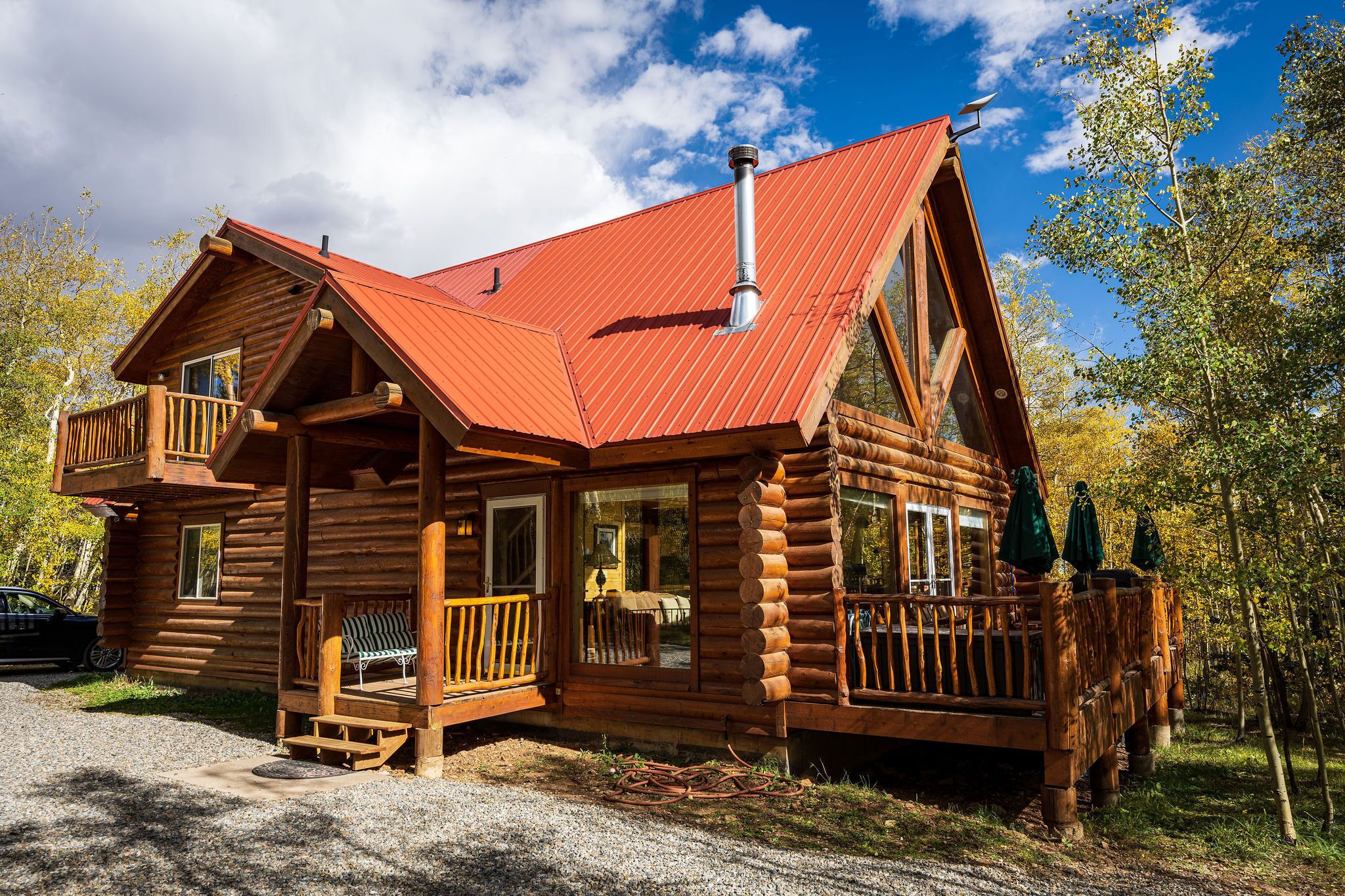A log cabin with a metal roof, wooden deck, and a chimney.