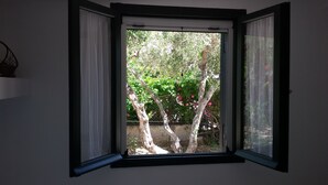 A room with a window overlooking a garden with trees and flowers. - Guest House  steps from ocean... (Chersonissos)
