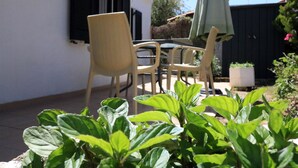 A patio with a table and chairs, surrounded by plants. - Guest House  steps from ocean... (Chersonissos)